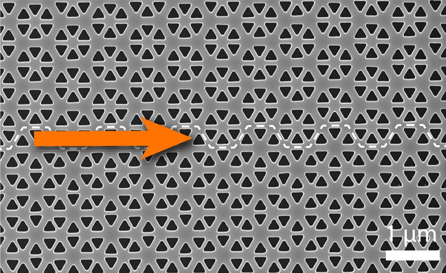 Electron microscopy image of topological photonic crystals in a perforated slab of silicon. The top and bottom crystal structures differ slightly; along the boundary between two parts (dotted line) light can be guided. The disparate mathematical description (topology) of the light fields in the two crystals prescribes that their boundary has to conduct light; that conduction is thus 'topologically protected'. @ AMOLF