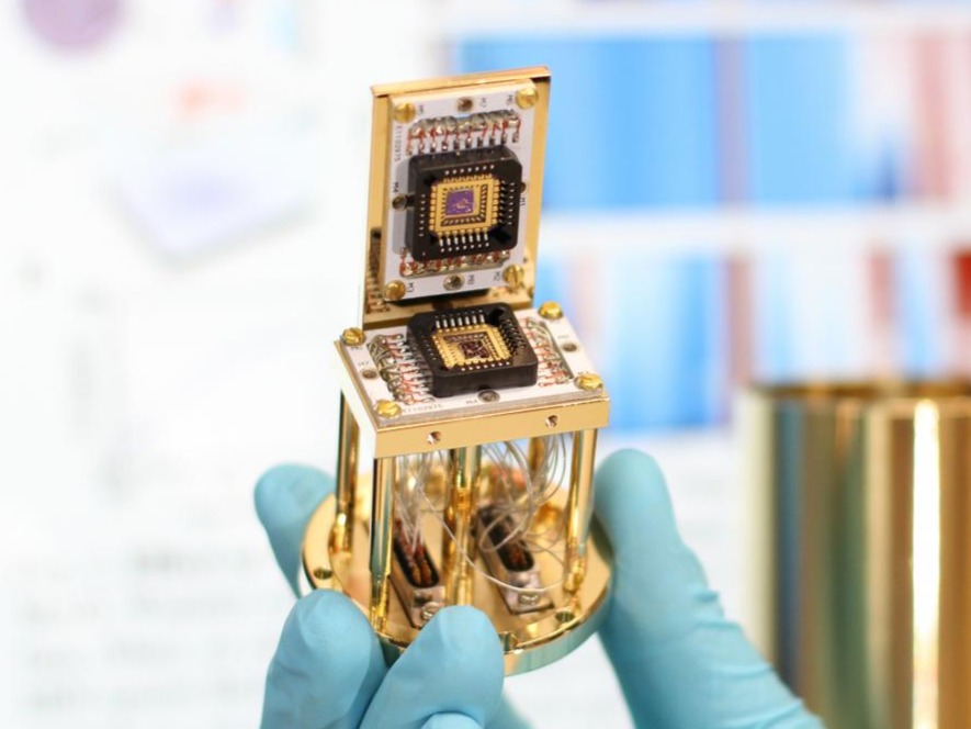 Close-up of the device (the twisted bilayer graphene structure is in the black center region on both squares with gold borders). This device is placed on the experimental setup within the fridge. @ ICFO