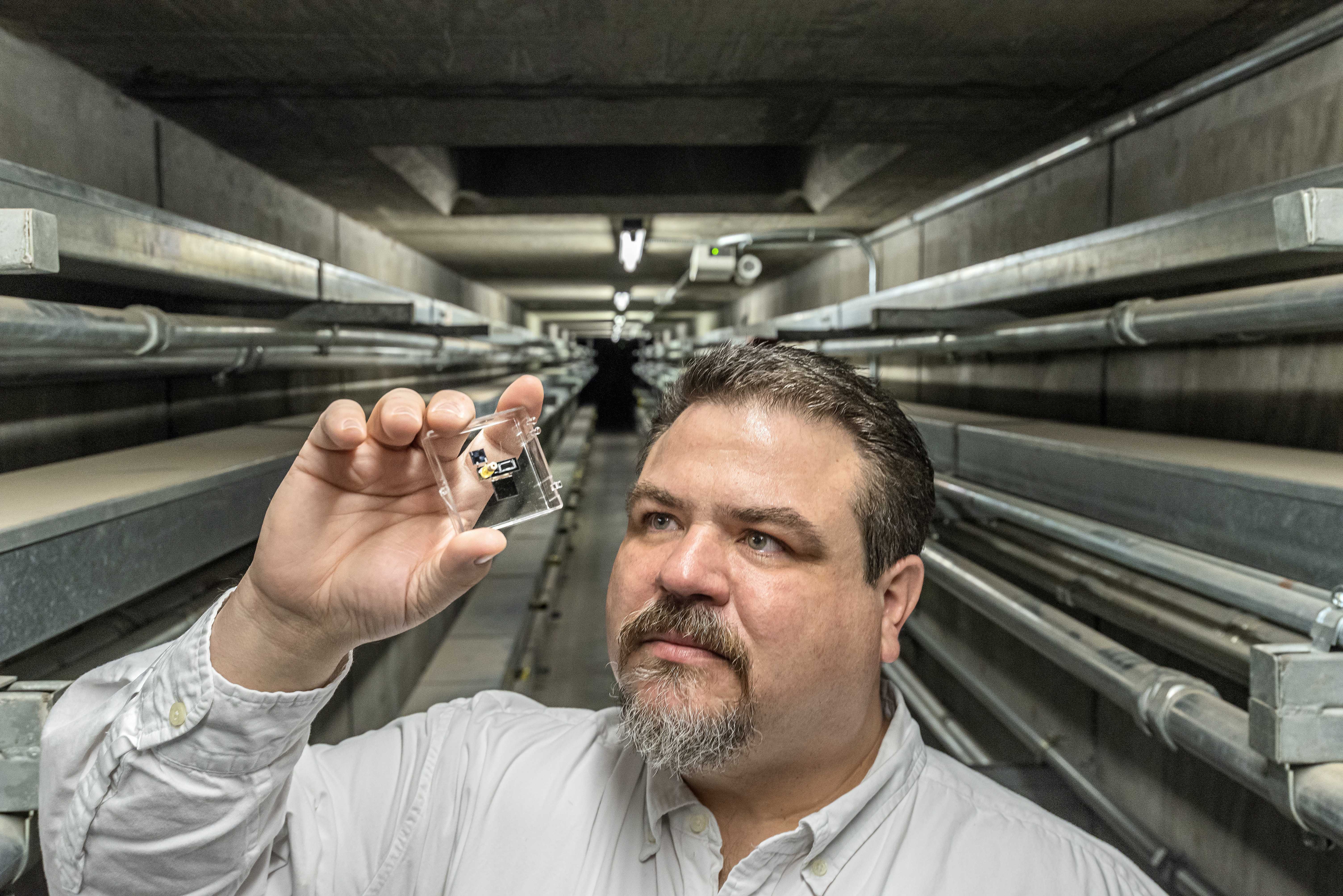 Joshua Whiting, an analytical chemist at Sandia National Laboratories, examines a gas sensor that could be used in a sensitive portable system to detect chemical weapons or airborne toxins. @ Randy Montoya / Sandia