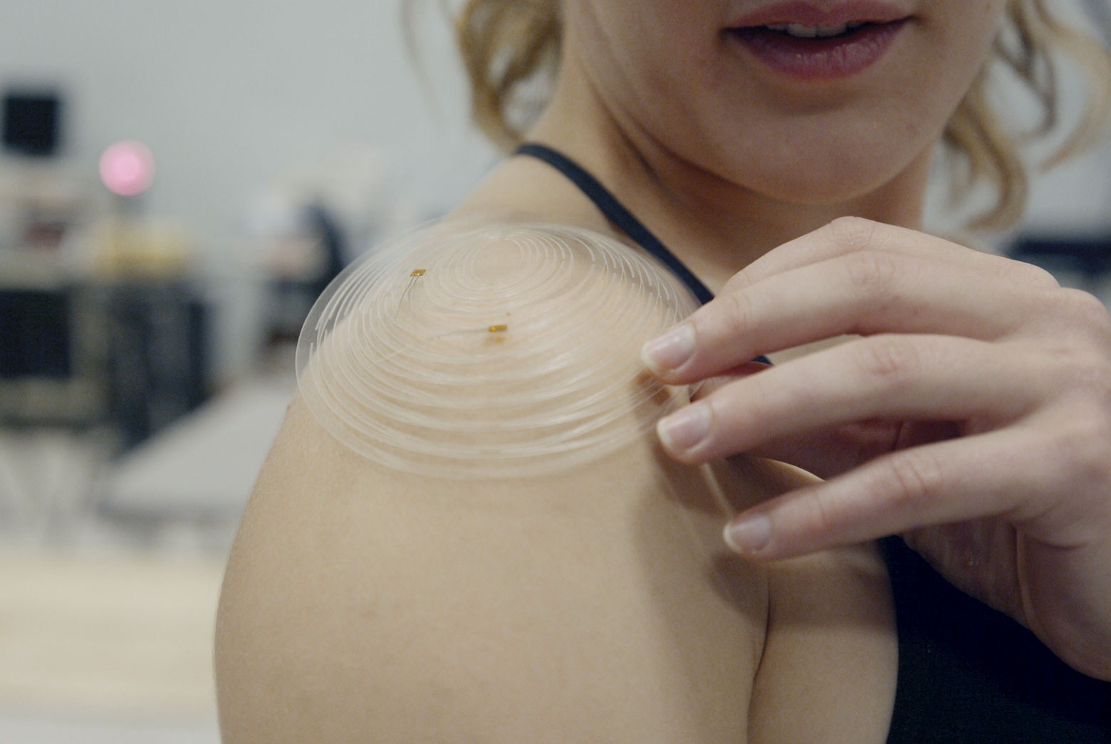 Erin Evke demonstrates how the cut patterns in the kirigami sensor open so that it follows the curve of her shoulder. This enables the sensor to be manufactured flat, which is crucial to making the device affordable. @ Levi Hutmacher, Michigan Engineering