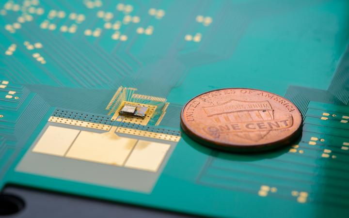 By only waking up a wireless device when necessary, the wake-up receiver (chip stack to the left of the penny) can cut down on power use and extend battery life. The system includes a miniaturized antenna (gold-colored plate below the receiver). @ David Baillot/UC San Diego Jacobs School of Engineering