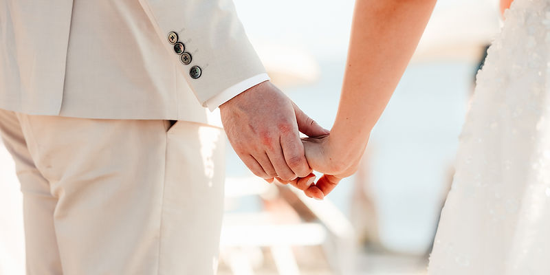 Detailaufnahme von sich haltenden Händen eines Brautpaares bei einer Destination Wedding am Strand.