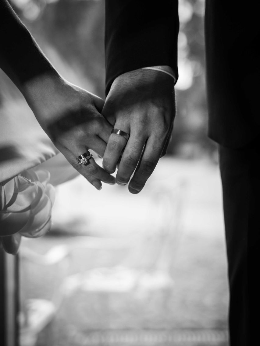 Schwarzweißaufnahme von Braut und Bräutigam, die sich an den Händen halten