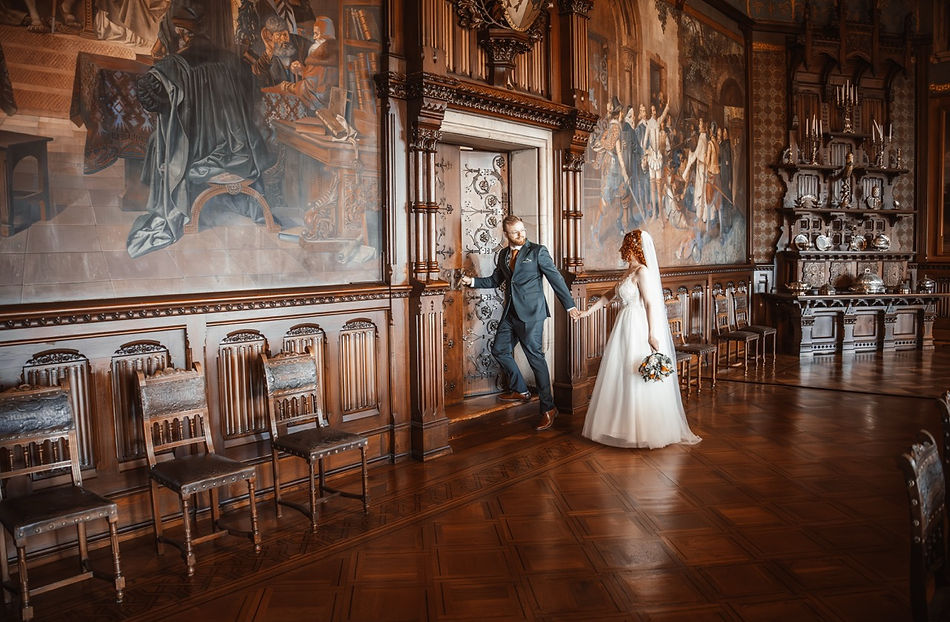 Brautpaar geht Hand in Hand durch den historischen Festsaal des Schlosses