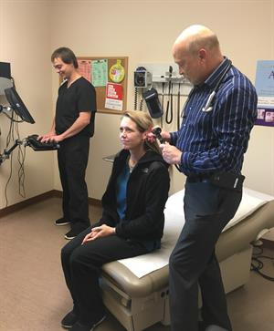 Lucas Short charts information as Dr. Laurance Choate examines mock-patient Whitney Carnahan, an employee of Umpqua Community Health Center