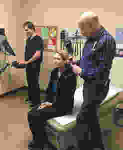 Lucas Short charts information as Dr. Laurance Choate examines mock-patient Whitney Carnahan, an employee of Umpqua Community Health Center