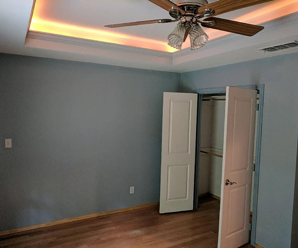 Outdated bedroom interior in Mount Pleasant, TX with blue walls, recessed ceiling lighting, and wood flooring ready for professional updates by Divine Layers.