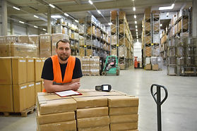 portrait of friendly warehouse worker in a forwarding agency - interior with forklift - tr