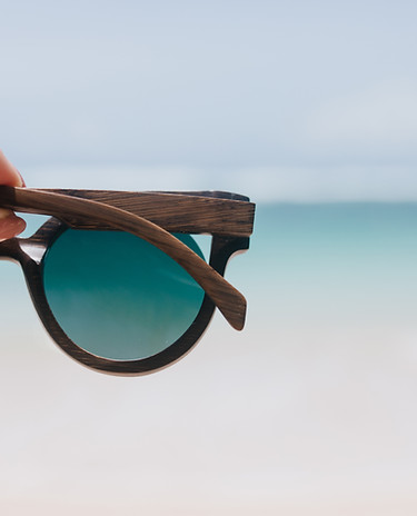 outdoor-photo-ocean-with-female-hand-foreground-woman-holding-summer-sunglasses-sea.jpg