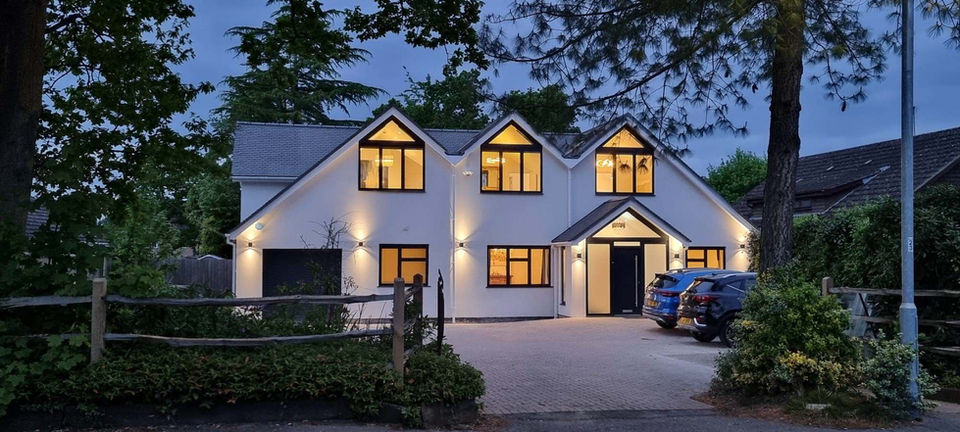 White modern home with lit windows and driveway at dusk My Site 4