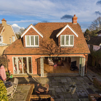Exterior view of a red brick house with open doors and windows. The Cottage Project.