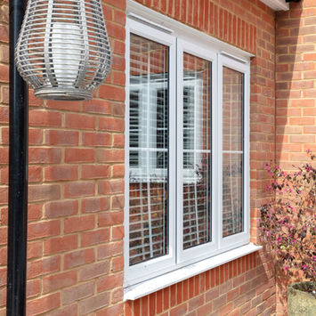 Exterior shot of a window with blinds, brick wall and decorative lamp.