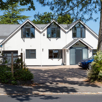 White modern house with multiple windows and car parked nearby the entrance.