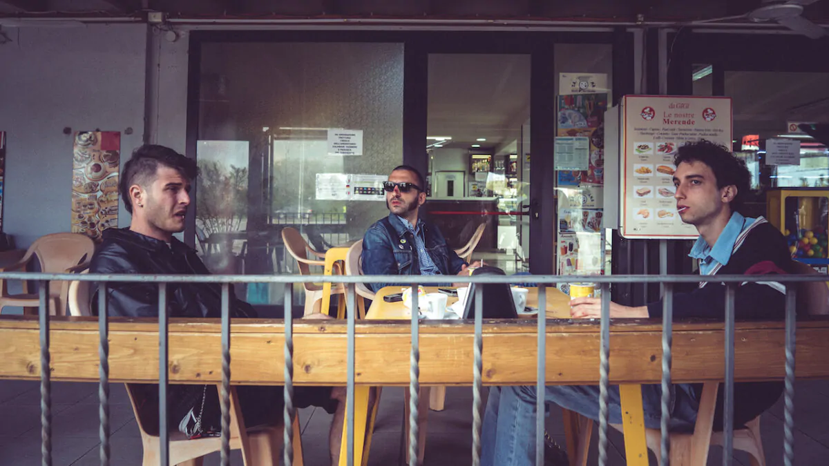 un frame del film Margini (Niccolò Falsetti e Francesco Turbanti, 2022) i tre protagonisti sono seduti ad un bar di provincia