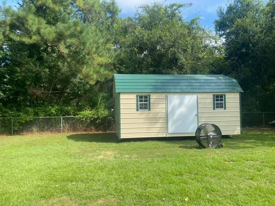 Cream-colored storage shed with a green roof on grass