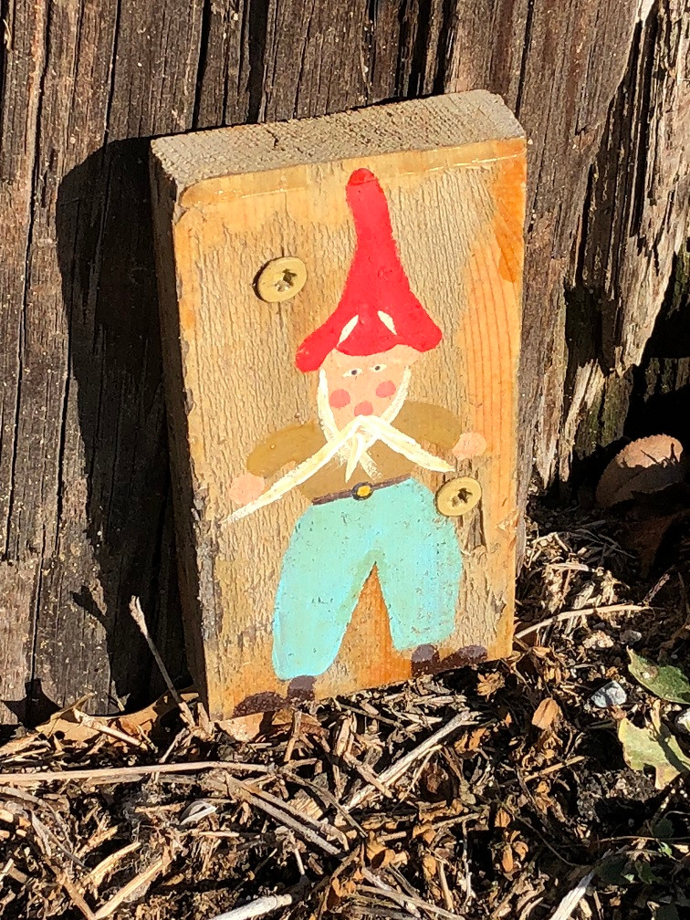 A gnome painted onto a small piece of wood is screwed onto the base of a telephone pole in downtown Shawnee, OK.