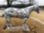 A horse sculpture painted with gears and faux iron plates stands in a wintery scene