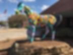 A horse sculpture painted with storybook characters stands outside a library.
