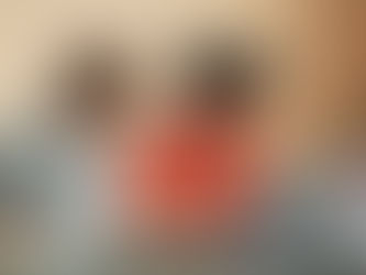 Two focused children working on a laptop with a "My Laptop, My Rules" sticker. One wears an orange sweater, the other a plaid shirt with headphones.