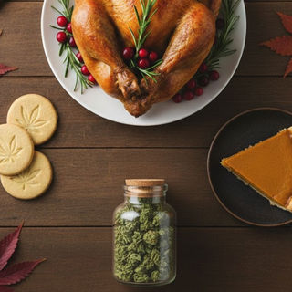 Thanksgiving-themed flat lay with a roasted turkey, pumpkin pie slice, cannabis leaf cookies, a jar of cannabis flower, and autumn leaves on a wooden table
