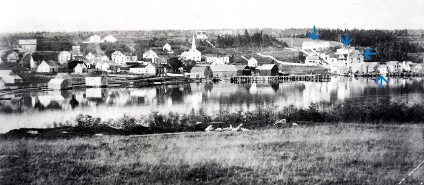 The view of Baddeck from Kidston Island. Blue Arrows show (from top to bottom) Duntulum Warehouse, Duntulum Cottage (site of present day MacLeod House), the Old Post Office, Campbell's Shipyard (site of present day Bras d'Or Yacht Club). ( Beaton Institute)