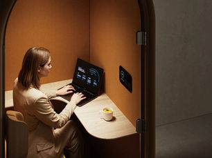 woman working in a lit Arc office pod