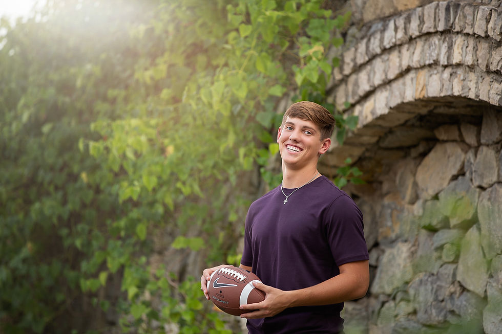senior boy poses with football
