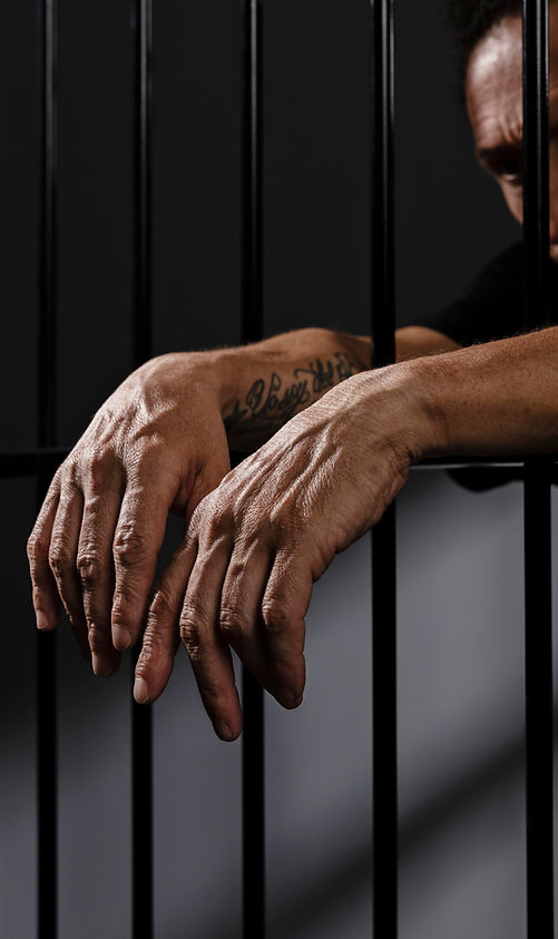 Hands hanging out of prison bars symbolizing the struggle for freedom and Mass Liberation's efforts in supporting reentry.