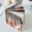 A custom photo album with a wooden cover, floral design, and initials "MLP." It shows a couple smiling. Books and a candle in the background. Perfect gift for your long distance relationship boyfriend.