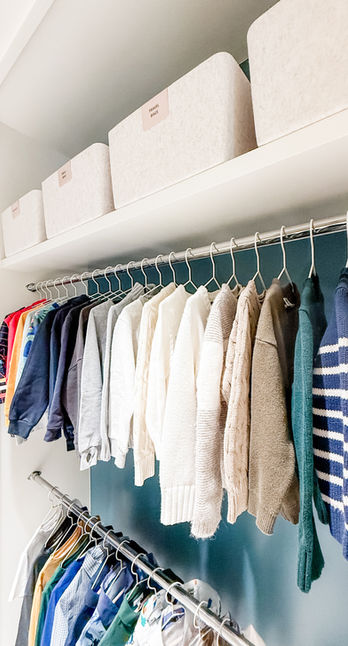 A little boys closet with bright teal walls and white shelves. Clothes are hung with white wire hangers, and accessories are stored in felt baskets with label clips. Aspen, Co.
