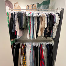 A reach-in closet organized with white hangers