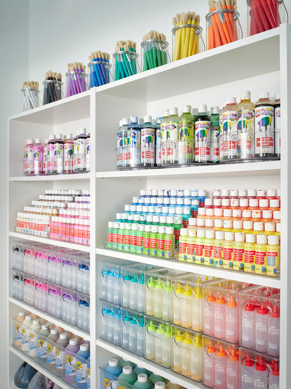 Paint organizing by color in clear bins on white IKEA shelves