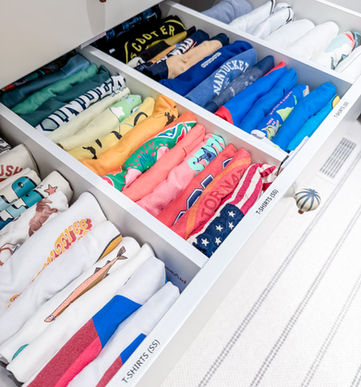 A little boy's t-shirt drawer divided by type and file folded by color.