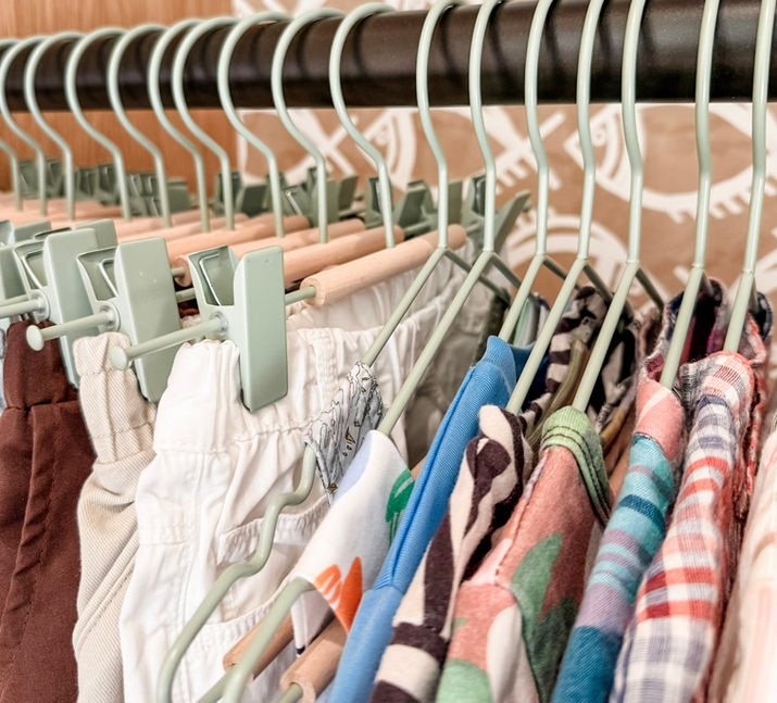 A kid's closet with metal green hangers and fish wallpaper in background. This is a vacation home in Hawaii.