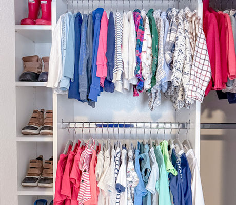 Kids' closet with custom Closet Factory system and color-coordinated clothing by KO Luxury Organizing in Golden, CO