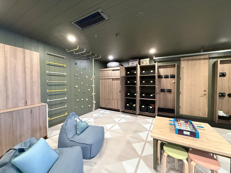 A large high-end playroom in Aspen, CO, with a climbing wall, climbing rope, and large cabinets with luxury bins.