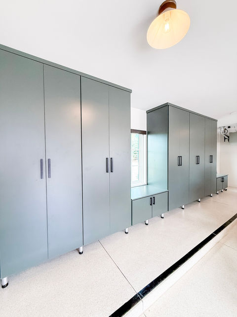 A sleek garage with floor-to-ceiling sage green custom cabinets and epoxy flooring creating a clean, high-end storage system — organized by KO Luxury Organizing in Cherry Hills Village, CO.