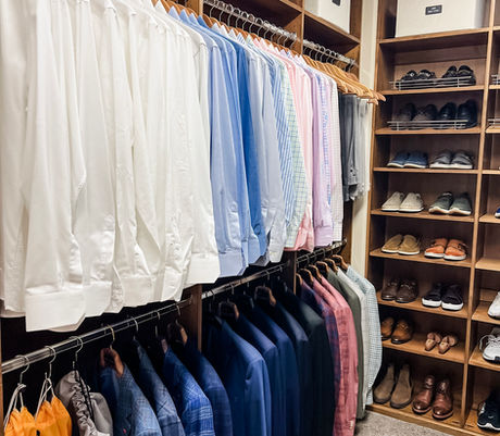 Luxury men's walk-in closet with color-coordinated shirts, jackets, and shoe shelving by KO Luxury Organizing in Cherry Hills Village, CO