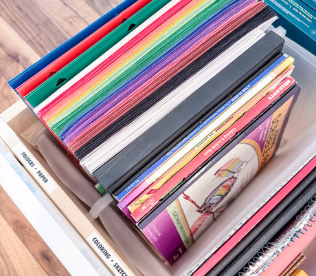 Colored paper, coloring books, and notepads organized vertically in a kids' art drawer by KO Luxury Organizing in Boulder, CO