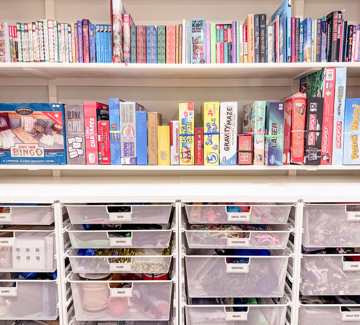 Books lined up neatly on a shelf, with games lined up like books on the shelf below, and four large Elfa drawer units below storing toys and games. Boulder, CO.