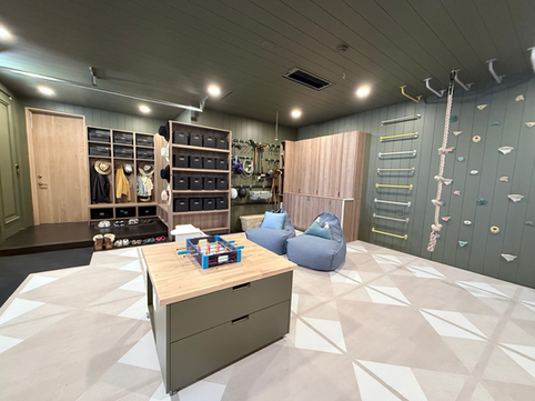 Luxury mudroom and garage that is used as a playroom and designed for family living, featuring custom cabinetry, labeled felt bins, and dedicated zones for gear, toys, and crafts.