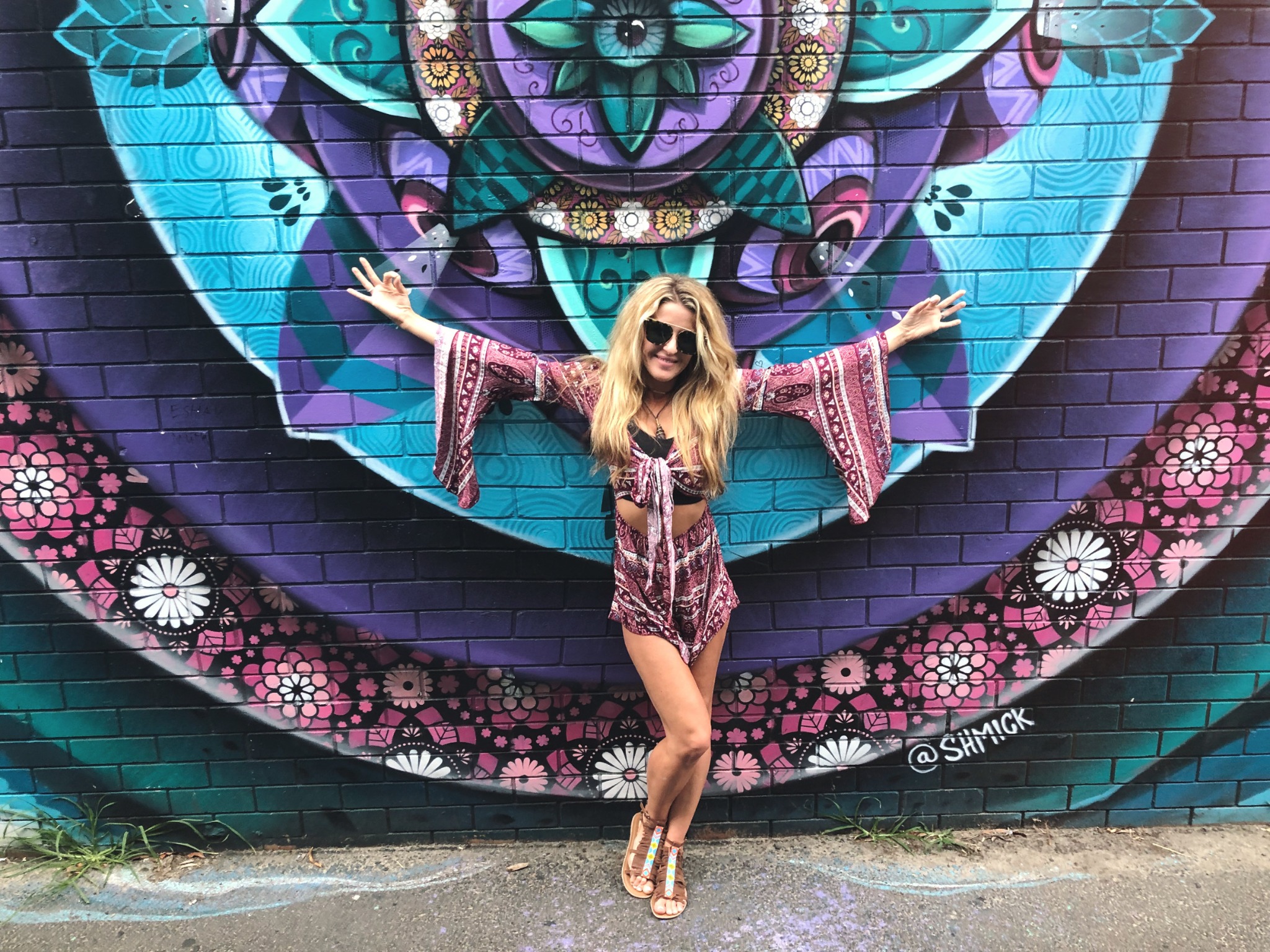 Rebecca Capps in front of a vibrant colorful mural