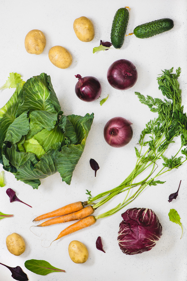 Colorful fresh vegetables and herbs on a light surface
