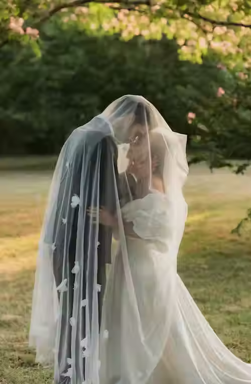 Couple de mariés enlacé sous un voile dans le parc du Château de Lisle en Médoc