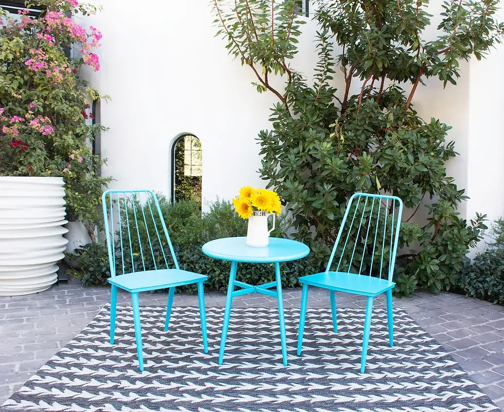 Charcoal and light grey chevron-patterned outdoor rug styled on a patio with bright turquoise metal chairs, a round table.
