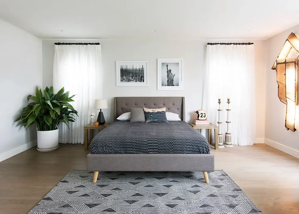 Modern bedroom featuring a black and white geometric area rug with triangle and stripe patterns, placed under a gray bed.