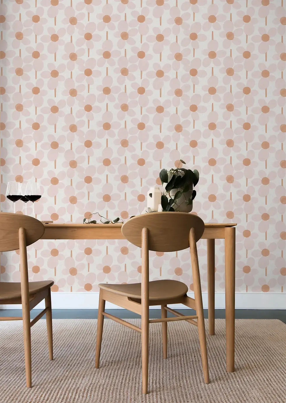 Dining room with wallpaper featuring a playful pattern of daisy-like flowers with blush pink petals, peach centers.