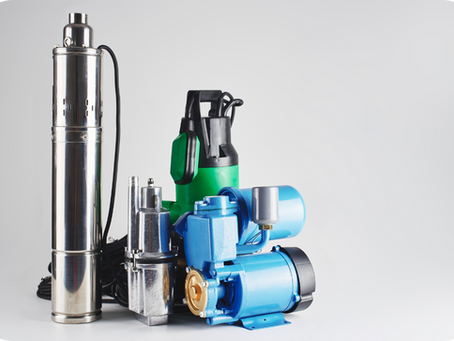 A display of various well pumps, including metal, green, and blue ones, on a light gray background. 