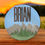 Miniatura: "The image shows a round wooden plaque with a scenic design. The plaque features a blue sky background with a silhouette of mountains and trees in the foreground. The name 'BRIAN' is prominently displayed at the top in large, bold, black letters. Below 'BRIAN,' the name 'Mosley' is written in a cursive, gold-colored font. The plaque is placed on a wooden surface, and the background appears to be an outdoor setting with a blurred landscape and a sunset or sunrise sky."