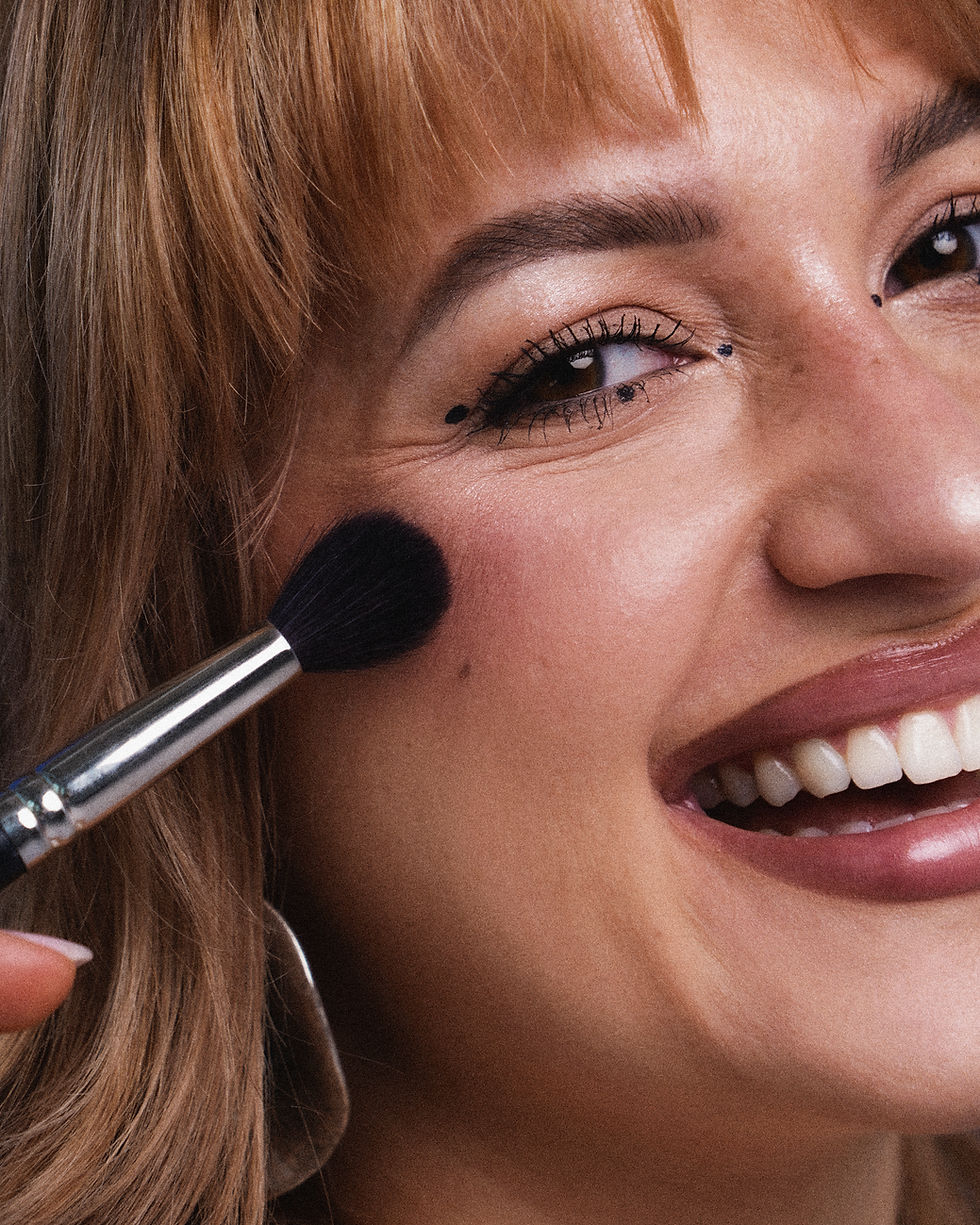 Zbliżenie na uśmiechniętą twarz Olivii Nowickiej muskaną pędzelkiem do makijażu